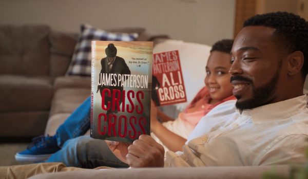 A boy and his father sit on a couch and read Criss Cross and Ali Cross