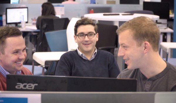 Three QA Symphony employees smile while discussing why they work at QA Symphony.