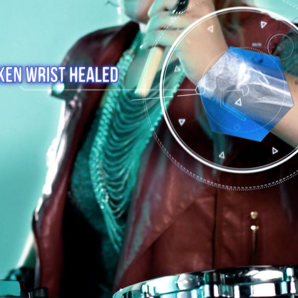 Closeup of a woman drummer in a red vest with a broken wrist healed.