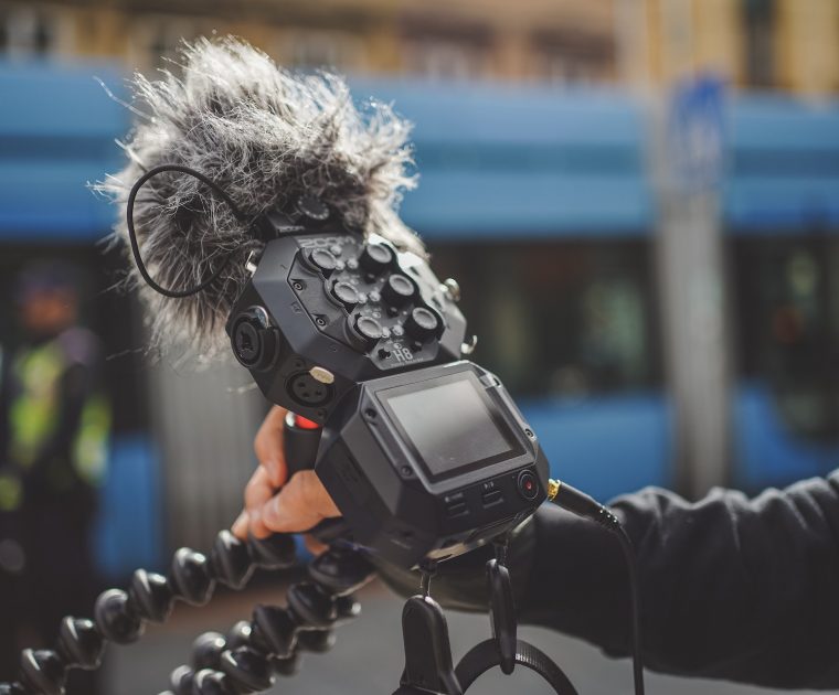 man records audio with a zoom recorder on a tripod