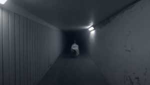 A cadaver covered by a sheet is wheeled down a dark hallway.