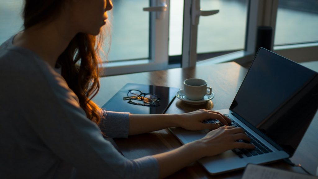 A woman types on a laptop at a desk dedicated for work to help her stay motivated.